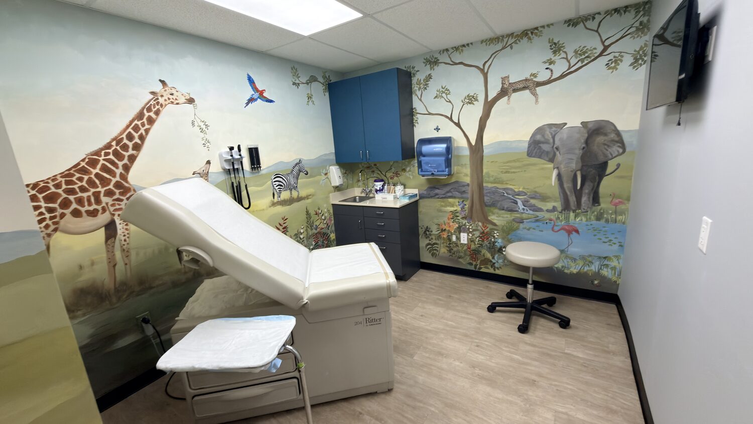 Pediatric exam room with a hand-painted safari mural